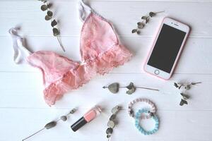 Woman's accessories on the wooden desk. Beautiful lace lingerie, flowers and nail polish. photo