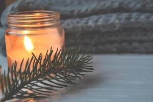 Merry Christmas and Happy New Year vintage background. Lighted candle on the white wooden desk. photo