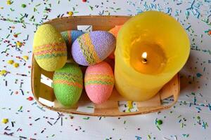 Colorful easter eggs with flowers and yellow candle in the basket. Beautiful easter background. Easter card. Homemade holiday decor. photo