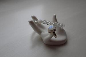 Silver ring with moonstone and bracelet from rock-crystal on porcelain hand. photo
