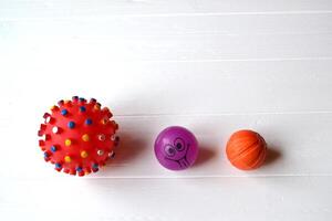 Balls for dogs. Rubber toys for pets on the white wooden background. photo