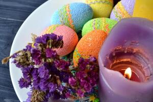 Colorful easter eggs with flowers and candles in the plate. Beautiful easter background. Easter card. Homemade holiday decor. photo