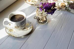 A cup of morning coffee and home decor on a white wooden table. photo