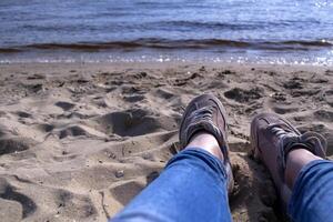 hembra piernas en zapatillas en un arena. relajarse en el playa. foto