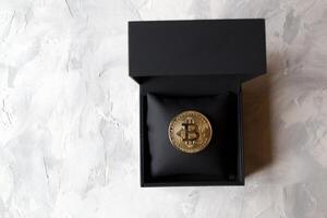 Golden bitcoin in a black box on textured background. Gold coin of cryptocurrency. photo