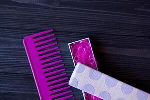 Beauty care tools. Beauty salon. Girl's paradise. Pink hair bands and comb on a dark blue wooden desk. Bright still life of beauty instruments. photo