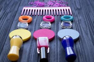 Colorful and bright cosmetics. Beauty care tools. Beauty salon. Girl's paradise. Nail polishes, sequins, pink hair bands and comb on a dark blue wooden desk. Bright still life of beauty instruments. photo