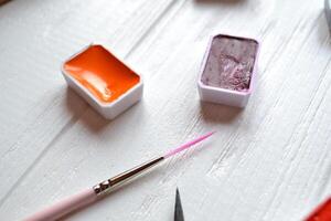 Tools for painting on the white wooden desk. Brushes and paints on the table. Painter's workplace. photo