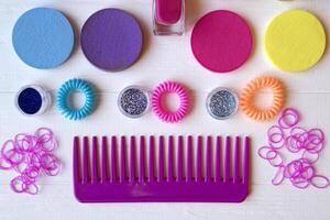 Colorful and bright cosmetics. Beauty care tools. Beauty salon. Girl's paradise. Nail polishes, sequins, pink hair bands and comb on the white wooden desk. Bright still life of beauty instruments. photo