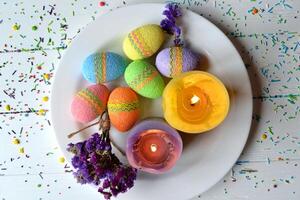 Colorful easter eggs with flowers and candles in the plate. Beautiful easter background. Easter card. Homemade holiday decor. photo