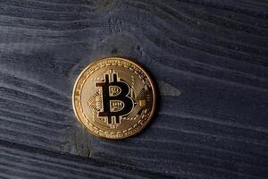 Bitcoin gold coin on the dark blue wooden background. photo