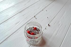 Colorful pearl beads in a glass jar on the white wodden background. photo