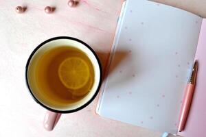 Comfortable female workplace with pen, notebook, beads, glasses and a mug of tea. photo