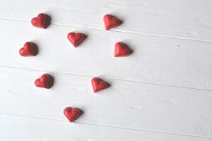 Red candies on the white wooden table. Background for greeting card on Valentine's day with place for text. photo