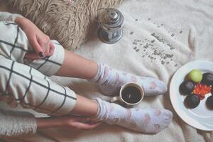 Woman relaxing in cozy place with sweets and a cup of tea. photo