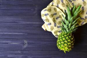 Pineapple and backpack on the table. Summer flat lay. photo