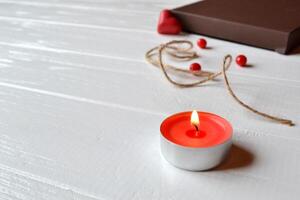 Candle, red hearts, rope and gift box on the white wooden desk. Valentine's Day. Background with place for text. photo