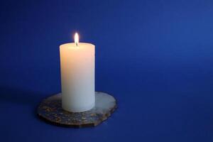 Burning candle on dark blue background. photo