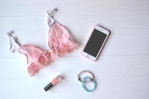 Woman's accessories on the wooden desk. Beautiful lace lingerie, flowers and nail polish. photo