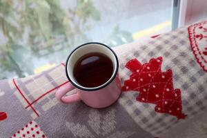 taza de té cerca ventana en un invierno tartán. foto