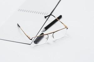 Blank notebook with pen are on top of white office desk table. Top view with copy space, flat lay. photo