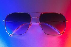 Stylish sunglasses shot using pink and blue abstract colored lighting with copy space. photo