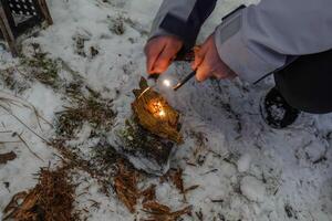 haciendo fuego con un fuego inicio en el naturaleza y invierno foto