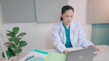 femmina medico utilizzando computer Lavorando a clinica o ospedale medico digitando su computer parlando con paziente per Aiuto dare consigli e spiegare malattia. video