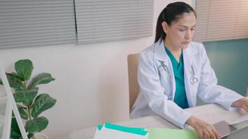 médecin dactylographie sur clavier séance dans hôpital Bureau travail dans Bureau santé ouvrier envoie message sur ordinateur clinique concept video