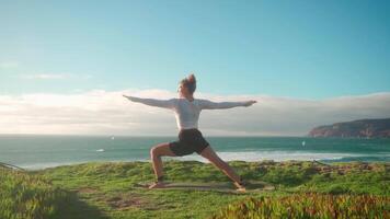 a woman doing yoga on a hill overlooking the ocean video