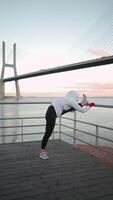 un mujer es calentamiento arriba en el puente cerca el agua video