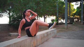 un' donna esercizio su un' calcestruzzo panchina nel un' parco video