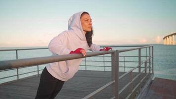 a woman in a hoodie is warming up on a dock video