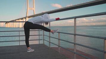 a woman is warming up on the bridge near the water video