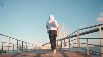 a person in a hoodie is running on a bridge video