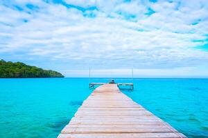 The wooden bridge stretches into the blue sea.Beautiful tropical beach with mountain clouds and sky.Relaxing at a good time photo