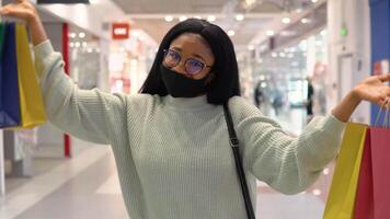 souriant fille africain content avec achats Sacs tandis que achats dans le supermarché. achats concept video