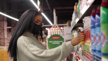 The girl in a mask chooses products on the shelves in the supermarket video
