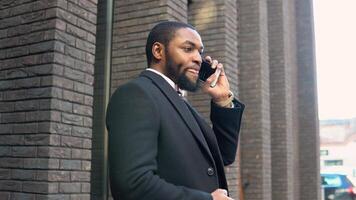 Young elegant black businessman talking on phone near the office center video
