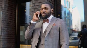 Young elegant african businessman talking on phone near the office center video