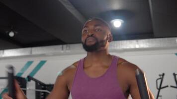 Bearded black man workout on elliptical trainer in the gym video