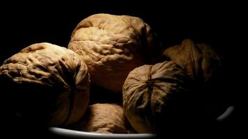 Walnuts nuts in a white bowl gyrating on black background with a cenital light video