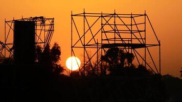 Sun hiding at sunset on structure of a stage of live music video