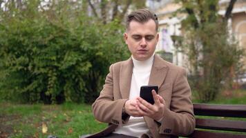 Elegant man uses smartphone while sitting on a bench on the street. Business. Social Networking video