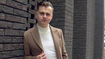 Portrait of a stylish businessman in brown coat on brick wall background video