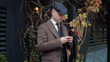 giovane elegante uomo d'affari utilizzando smartphone su strada. un' uomo sms messaggi, imbrogliare su il suo smartphone vicino il ufficio centro. attività commerciale. sociale networking video