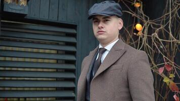 retrato do uma à moda homem de negocios dentro Castanho casaco e chapéu em de madeira fundo em rua video