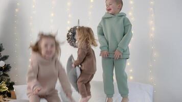 niños saltando en el cama con almohadas cerca Navidad decoraciones video