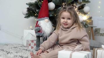 dulce pequeño niña muestra Hola sentado cerca Navidad árbol video