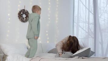 chico y niña saltando en el cama con almohadas cerca Navidad decoraciones video